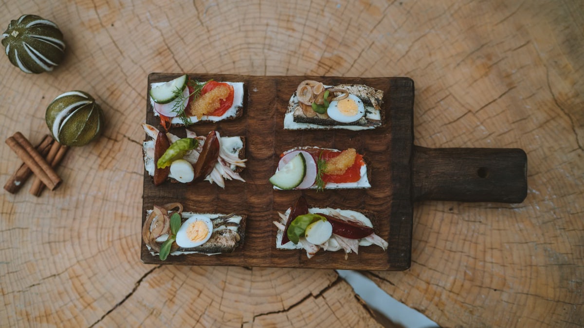 Top view of holiday appetizers on a wooden board with festive elements, creating a cozy rustic feel.